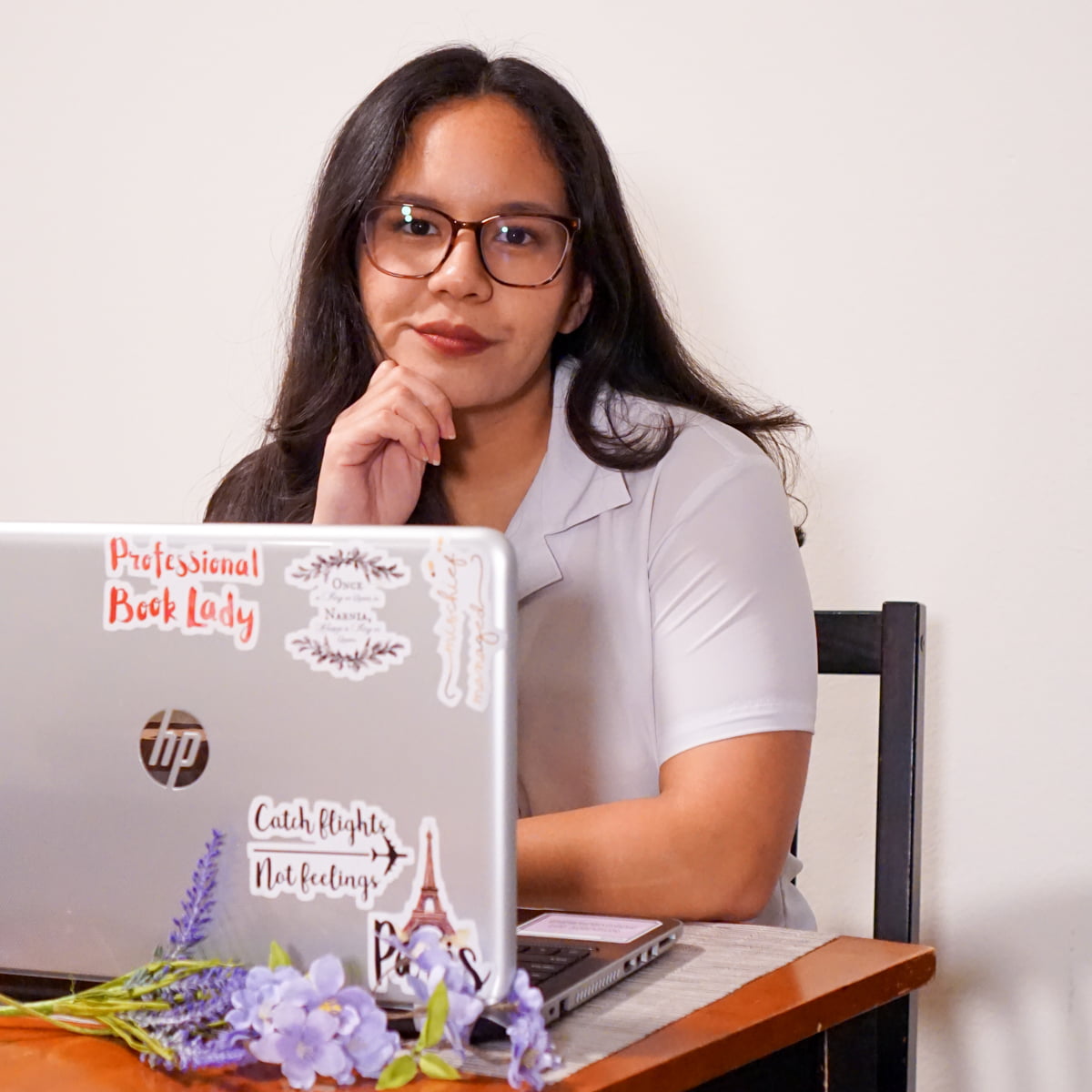 Picture of Yasmin sitting in front of a laptop that's decorated with several stickers | About Me, The Yasmin Diaries