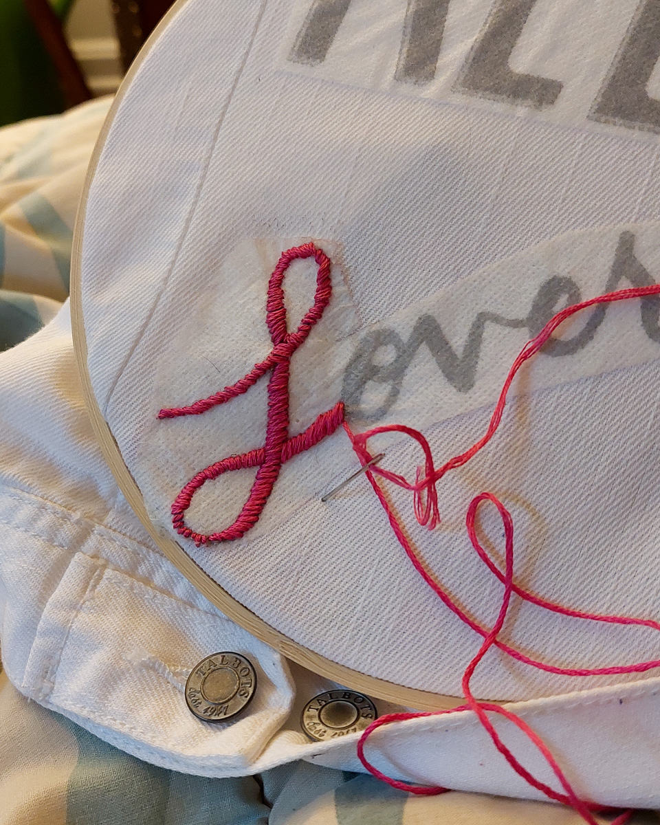 A close-up image of the embroidered jacket, featuring an embroidered L from Lover.